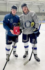 Two ice hockey players from the Bristol Pitbulls team holding a Daniel Baird Bleed Control Kit donated by money raised by Adam's Angels.