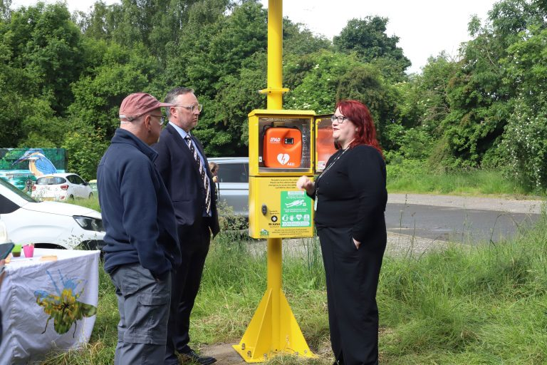 Representatives from St John Scotland and RSPB standing with Turtle's wind and solar powered defib cabinet at RSPB Baron’s Haugh Nature Reserve